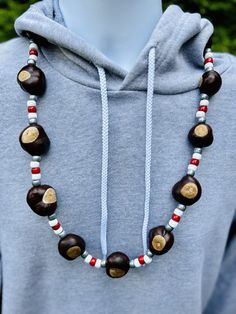 Football Helmet Pattern Buckeye Necklace - the new essential necklace for die-hard football fans! This necklace is your game day must-have, perfect for tailgates, family hangouts, and games at the Shoe. Get ready to flaunt your Buckeye pride with our classic pearl-finish pony bead style necklace. The scarlet, white, and gray beads capture the Ohio State spirit effortlessly. What sets our necklace apart? It's all about the Buckeyes - 14 top-notch, Columbus-grown Buckeyes, a cut above the rest. We Buckeye Necklace Diy, Buckeye Decorations, Buckeye Necklaces, Buckeye Wreath, Ohio State Crafts, Buckeye Crafts, Helmet Pattern, Ohio Buckeyes, Fall Necklace