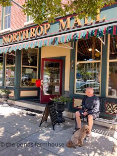 a man sitting on a bench in front of a store with a dog next to him