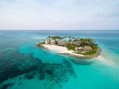 an island in the middle of the ocean surrounded by palm trees and blue water with a boat on it