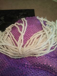 a purple and white piece of cloth with yarn on it