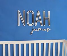 a white crib in front of a blue wall that says noah james