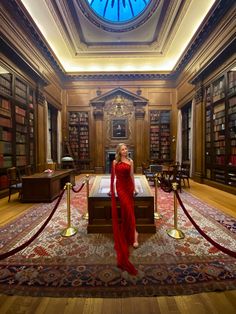 a woman in a red dress standing in a library