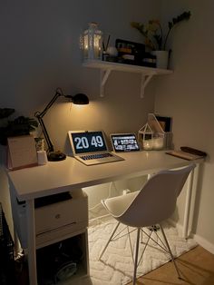 a laptop computer sitting on top of a white desk next to a lamp and chair