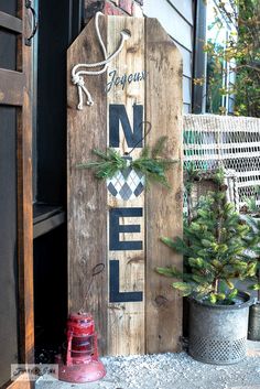 a wooden sign sitting on the side of a building next to a christmas tree and fire hydrant