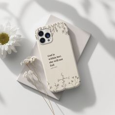 a white phone case sitting on top of a table next to a flower