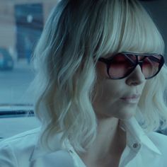 a woman with blonde hair and sunglasses sitting in a car looking off to the side