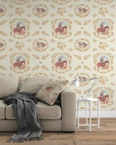 a couch sitting in front of a wallpaper with horses on it and a lamp next to it