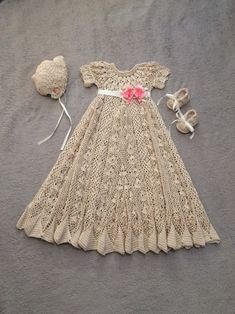 a crocheted dress and hat are laid out on the ground next to a flower