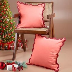 two red pillows sitting on top of a chair next to a christmas tree and presents