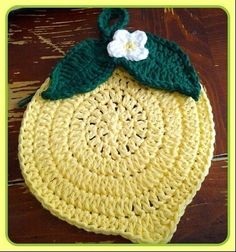 a crocheted lemon with a white flower on it's green leafy top