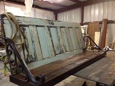 an old wooden bench sitting inside of a building next to other wood and metal items