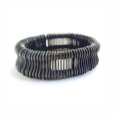 a black and white photo of a coil bracelet with two rows of metal rings on it