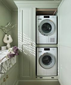 a washer and dryer are in the corner of a room with green walls