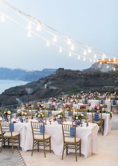 an outdoor dining area with tables and chairs set up on the cliff overlooking the ocean