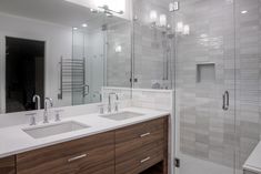 a bathroom with two sinks and a walk in shower next to a large mirror on the wall