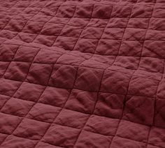 a red quilted bed spread is shown in close up view, with no sheets on it