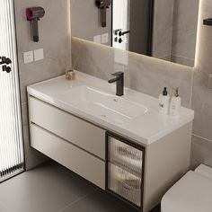 a white bathroom sink sitting under a mirror next to a toilet and trash can in front of it