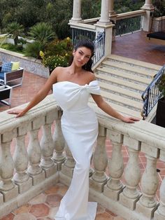 a woman in a white dress standing on a balcony