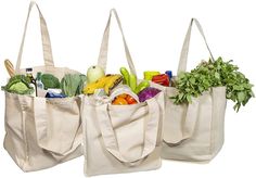 three grocery bags filled with vegetables and fruits, all in different colors tote bags