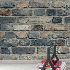 a stack of books sitting on top of a table in front of a brick wall