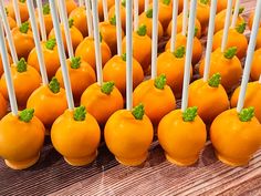 there are many orange cake pops with green leaves on them and white sticks sticking out of them