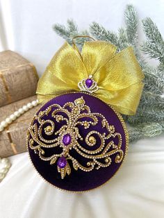 a purple ornament with a yellow bow on it and some decorations around it