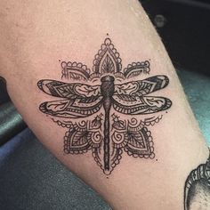 a black and white photo of a dragonfly tattoo on someone's left leg