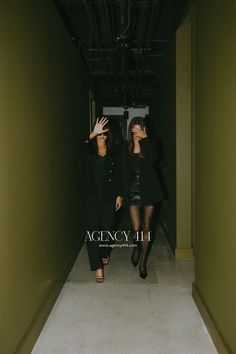 two women walking down a hallway with their hands in the air and one holding her head