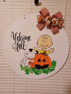 a welcome fall sign hanging on the side of a wall with a dog and pumpkin