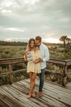 a man and woman standing on a wooden bridge