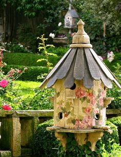 a bird house sitting in the middle of a garden