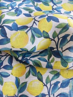 a yellow and blue fabric with lemons on the leaves, as well as green leaves