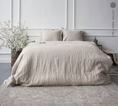 a large bed sitting on top of a wooden floor next to a plant in a vase