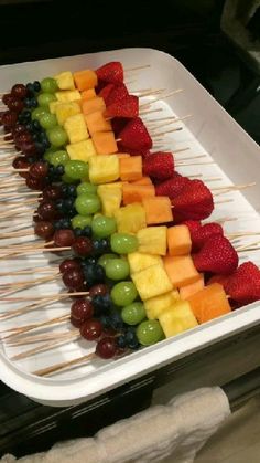 fruit skewers are lined up on a tray