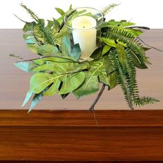 a candle and some green leaves on a table