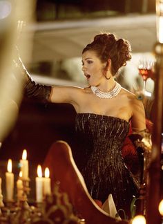 a woman standing in front of a chandelier filled with candles