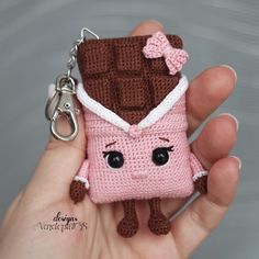 a hand holding a small crocheted keychain with a pink and brown piece of food on it