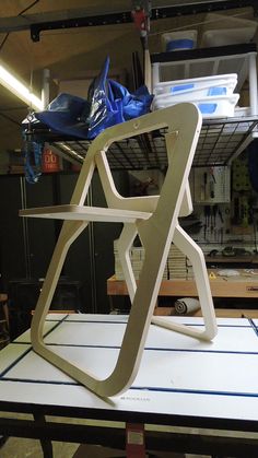 a white chair sitting on top of a table in a room filled with shelves and tools