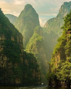 the mountains are covered in green vegetation and trees, with a river running between them