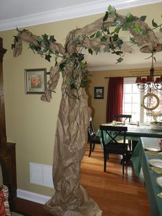 a dining room with a table and chairs covered in brown tissue paper next to a tree