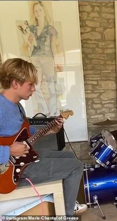 a young man playing an electric guitar in front of a tv