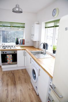 a kitchen with white appliances and wooden counter tops next to a window in the corner