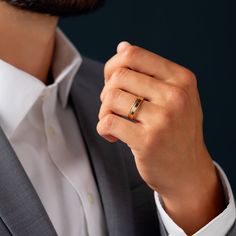 a man in a suit holding his wedding ring