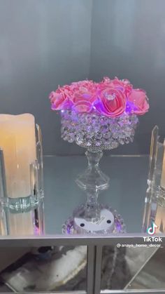 a glass table topped with candles and pink flowers