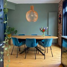 a dining room table with blue chairs and a plant hanging from it's ceiling