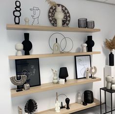 some shelves with vases, pictures and other items on them in a white room