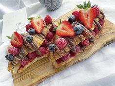 a piece of bread with fruit on it sitting on top of a wooden cutting board