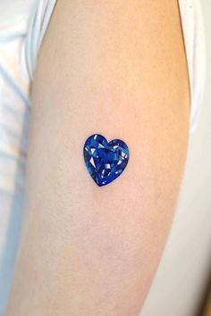 a blue heart shaped diamond tattoo on the right side of her left arm and shoulder