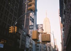 traffic lights and street signs on a city street with tall buildings in the back ground