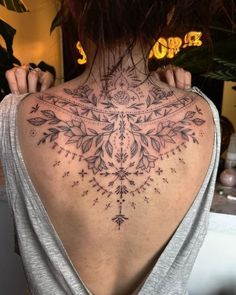 the back of a woman's neck with an intricate tattoo